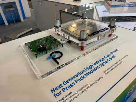 Acrylglassockel aus farblosem Material mit mehreren Bohrungen, Gewinden, und umlaufender Fase. Auf dem Sockel wurden mehrere Elektronikbauteile als Display für einen Messestand verschraubt. Auf dem Sockel sind zwei Firmennamen mit buntem Acrylglas in Taschen eingelassen und verklebt worden.