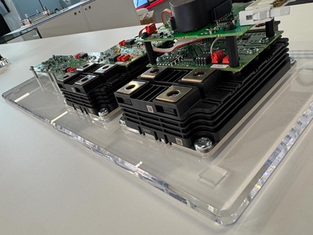 Acrylglassockel aus farblosem Material mit mehreren Bohrungen, Gewinden, und umlaufender Fase. Auf dem Sockel wurden mehrere Elektronikbauteile als Display für einen Messestand verschraubt.