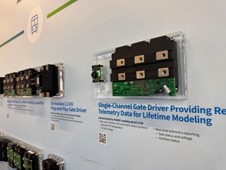 Foto zeigt eine Wand eines Messestandes, an der mehrere Elektronikbauteile auf einzelnen Acrylglassockeln an der Wand befestigt wurden.